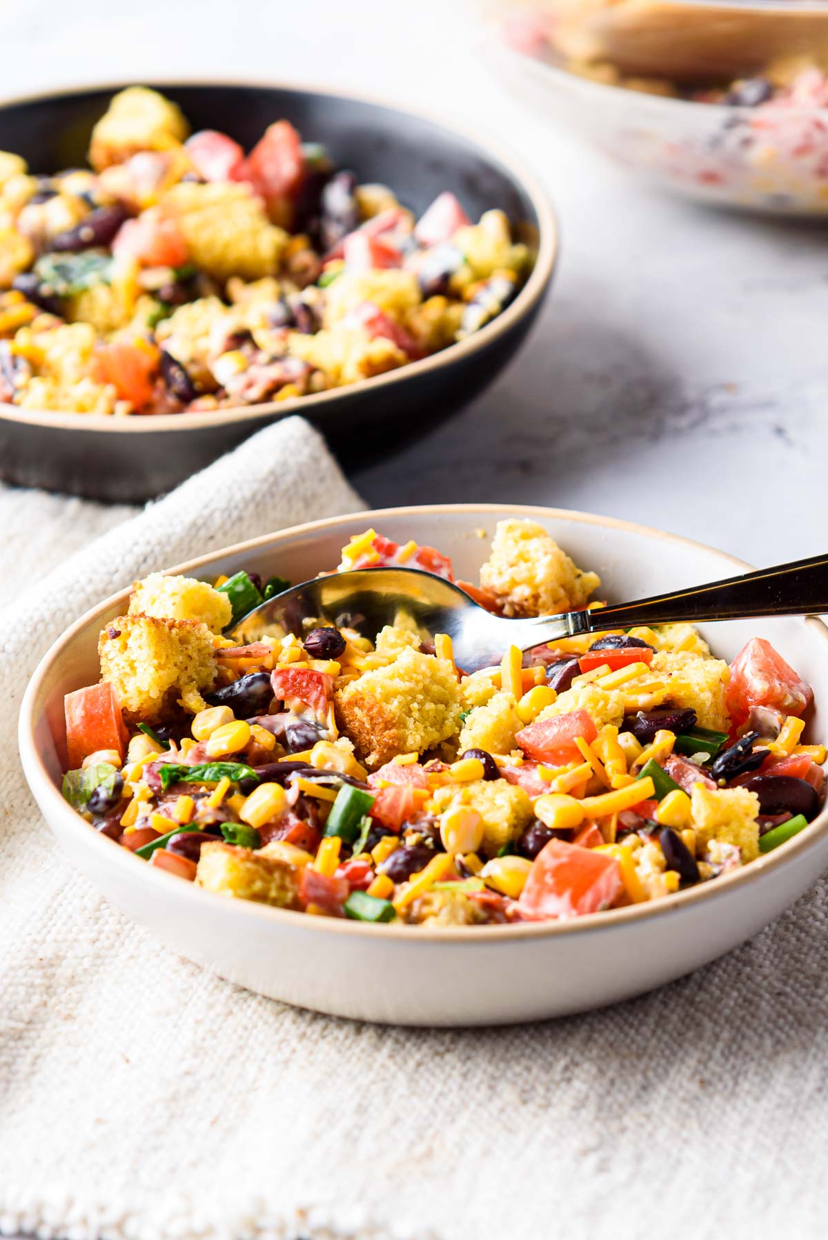two bowls of cornbread salad with serving spoon