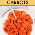 Sliced cooked carrots in a round bowl with a spoon.