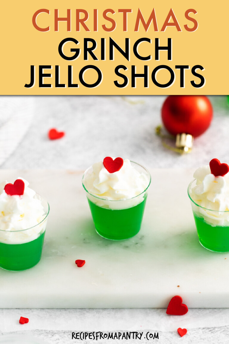 Three green jello shots with whipped cream and red heart candy on top