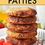 A stack of five turkey patties on a plate with cherry tomatoes on the side