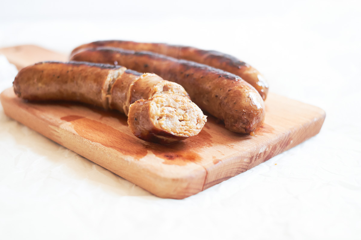 the finished italian sausages on a cutting board and sliced