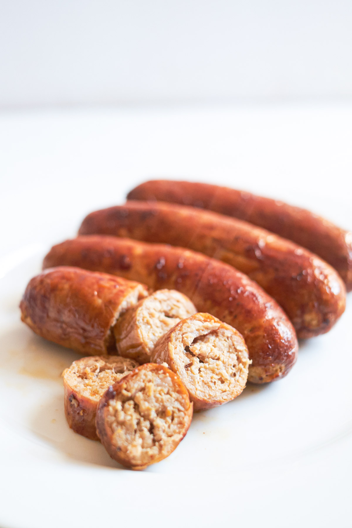 the completed Air Fryer Italian sausage sliced and served on a white plate
