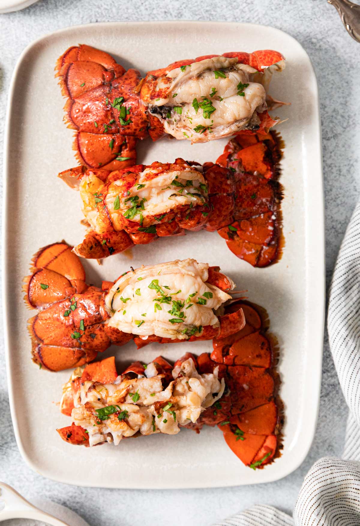 top down view of cooked lobster tails on a white platter