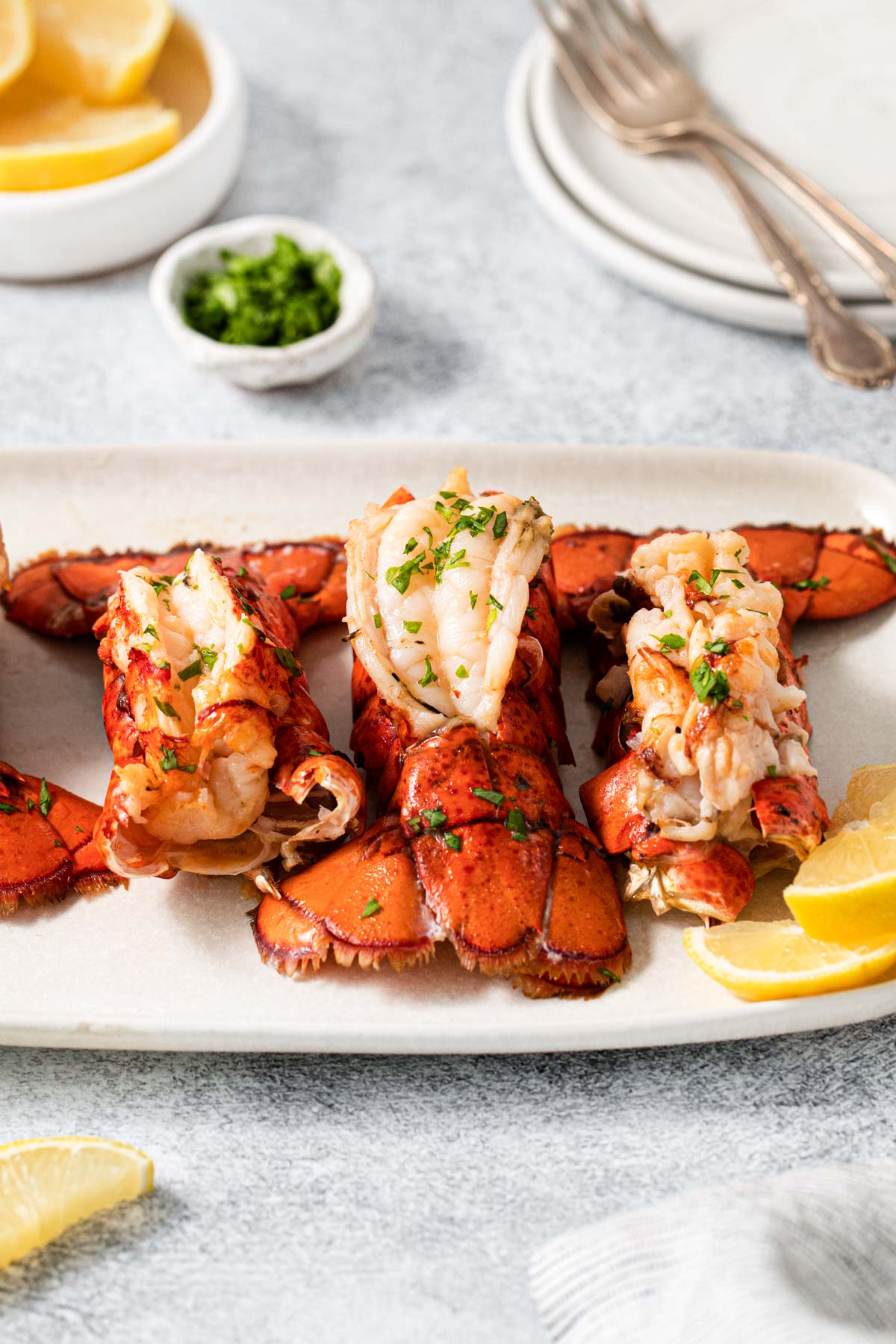 three lobster tails served on a white plate