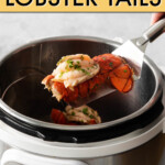 A lobster tail being lifted out of an instant pot with a metal spatula