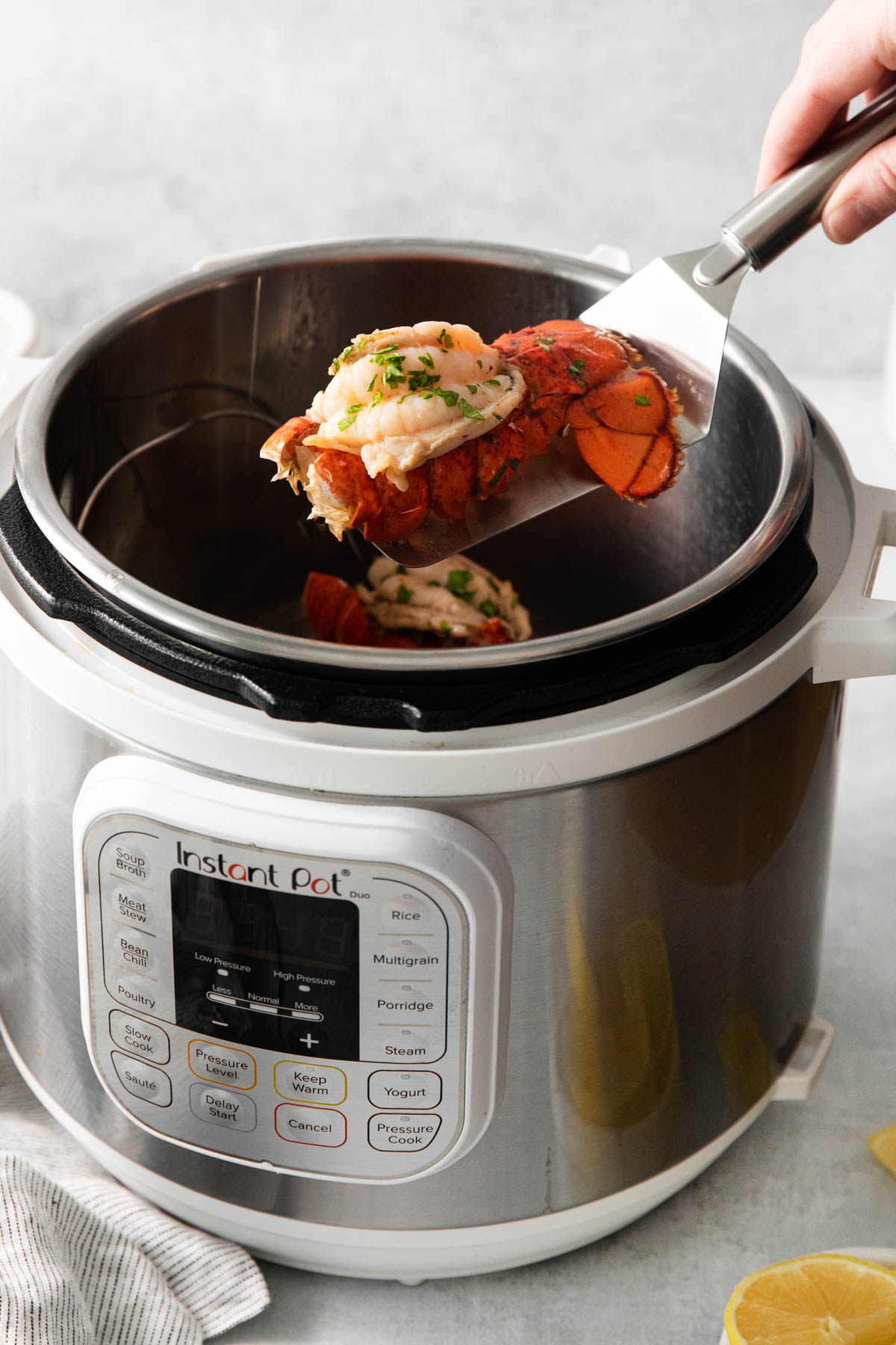 one lobster tail being removed from the instant pot