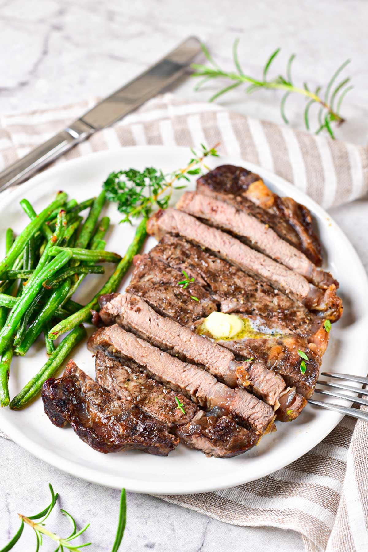 air fryer steak sliced, topped with butter and sauce, and ready to serve
