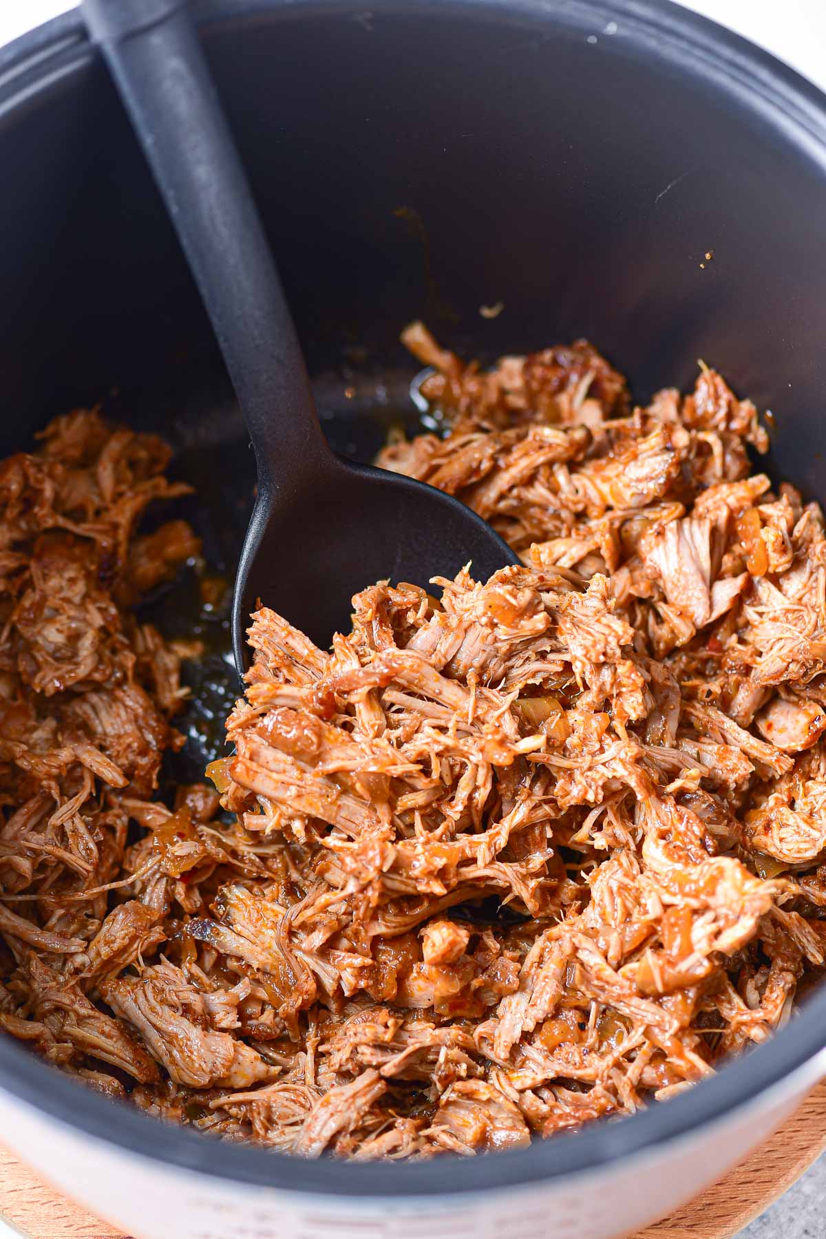 a serving spoon scooping out some of the dutch oven pulled pork