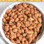 Overhead view of pinto beans in a bowl with a spoon