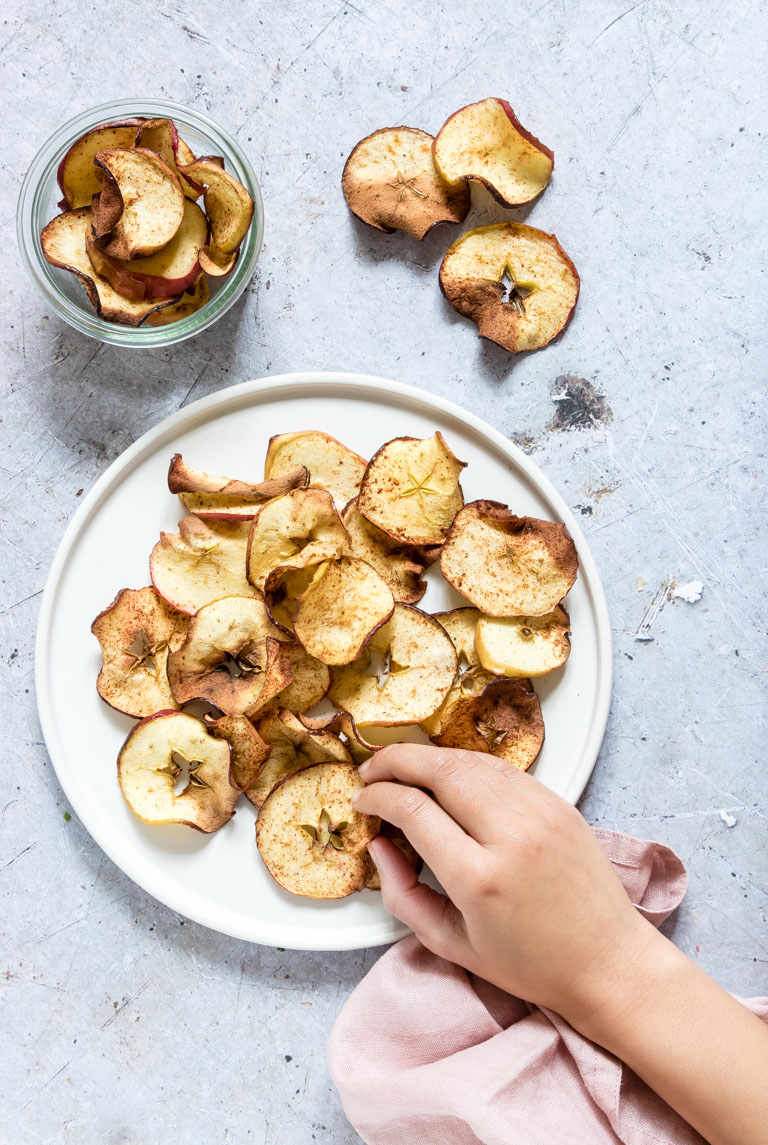 a hand reaching for air fryer apple chips