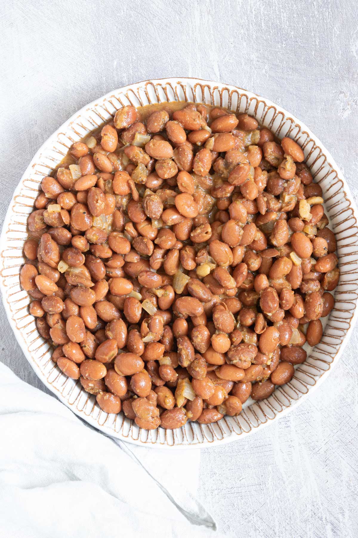 how to cook canned pinto beans recipe served in a white bowl with cloth napkin