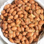 the finished how to season pinto beans recipe with a serving spoon and cloth napkin