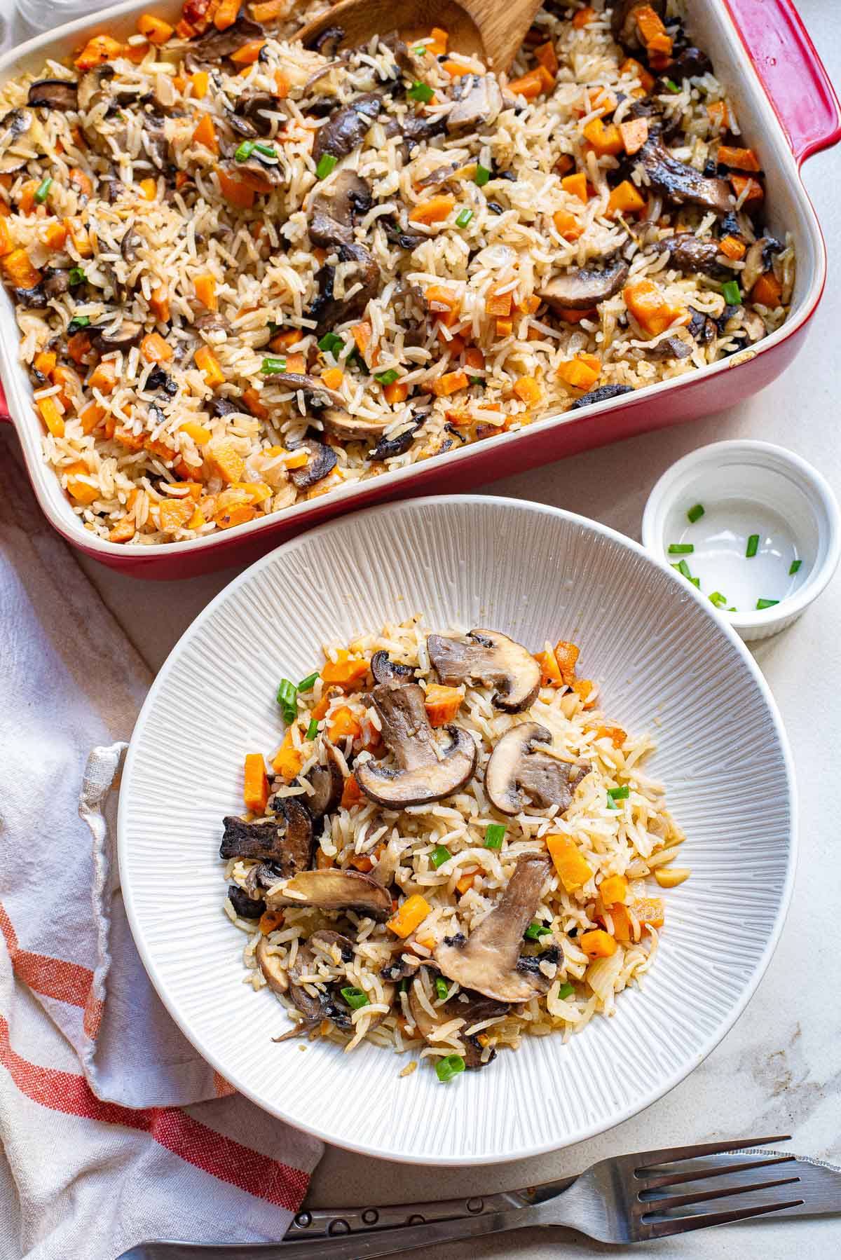 the finished mushroom rice in a baking dish with one portion in a bowl