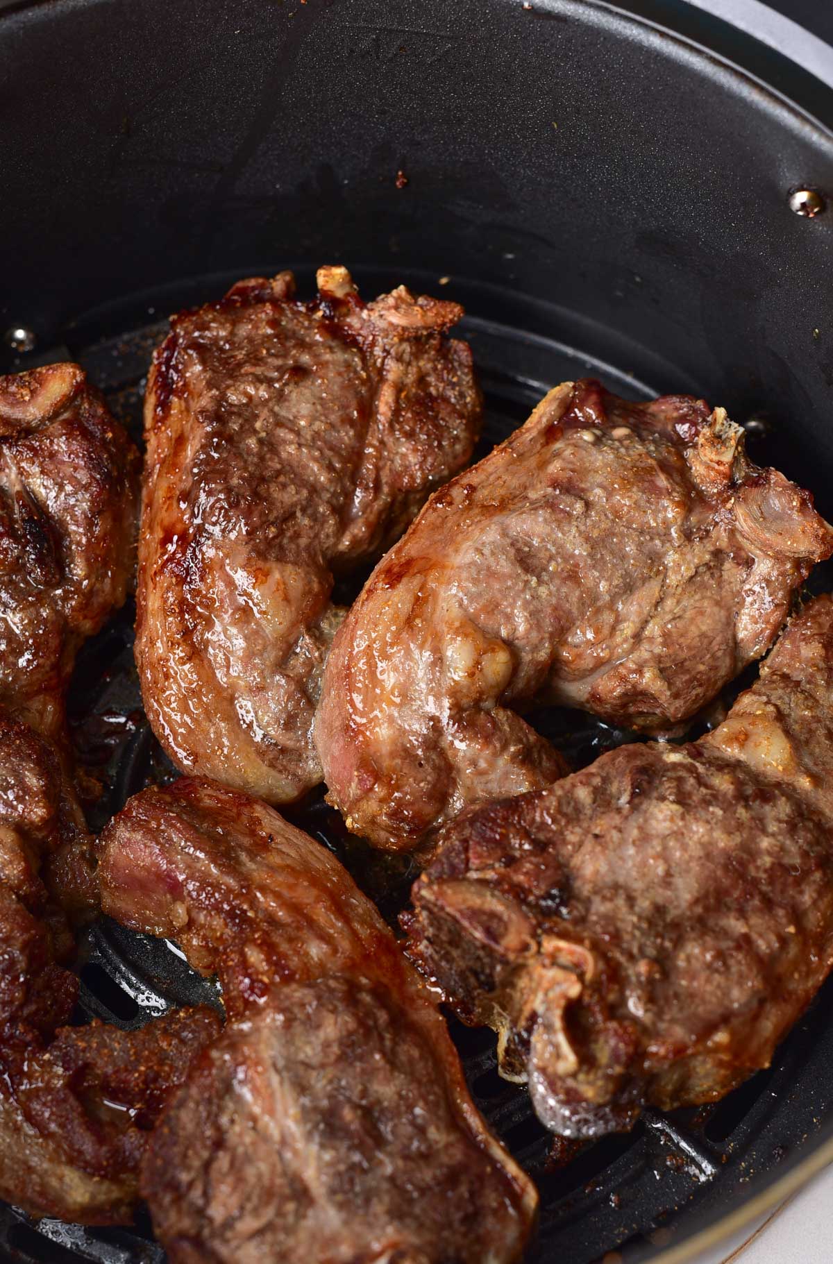 close up view of the cooked lamb chops in the air fryer basket