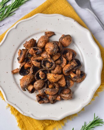 the completed air fryer mushrooms recipe served on a white plate on top of a yellow placemat