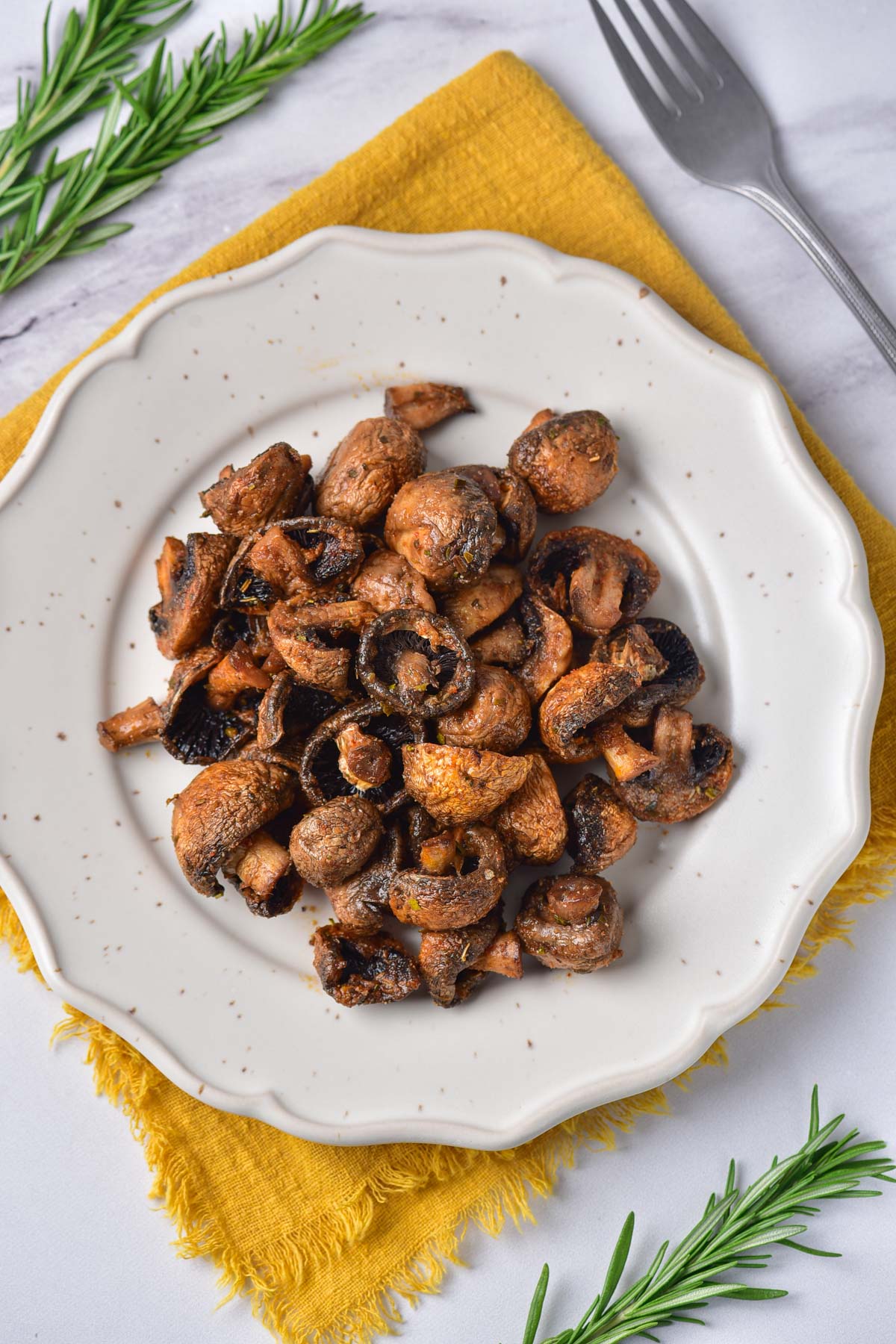 the completed air fryer mushrooms recipe served on a white plate on top of a yellow placemat