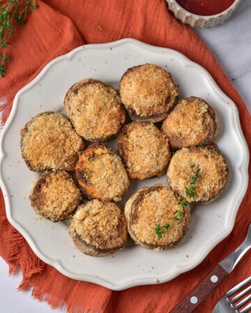 top down view of the finished air fryer stuffed mushrooms on a white serving plate