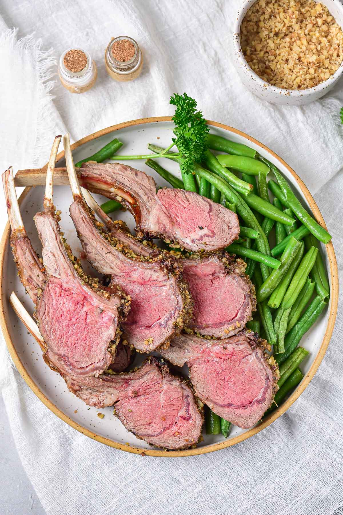 the sliced air fryer rack of lamb on a dinner plate with green beans