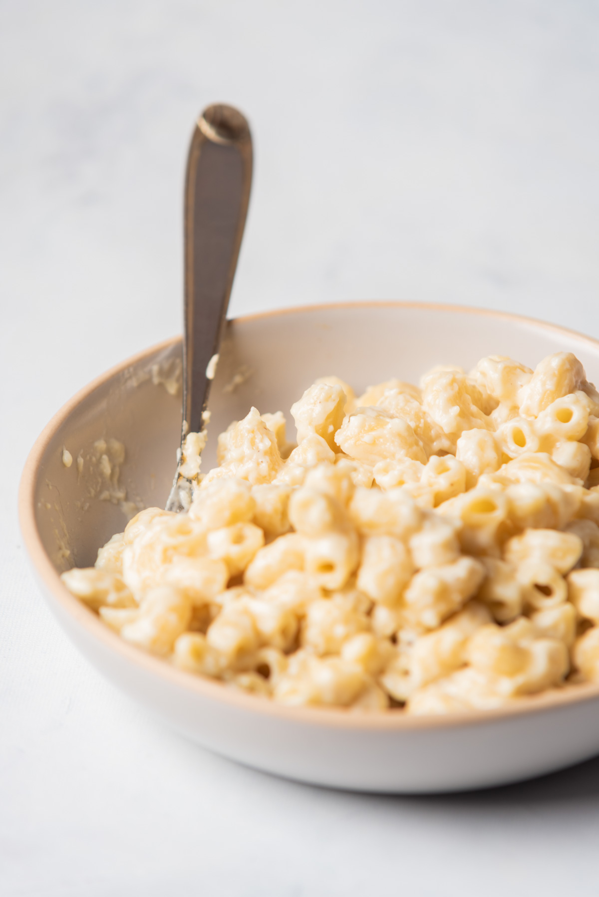 a bowl of white cheddar mac and cheese with a spoon inside