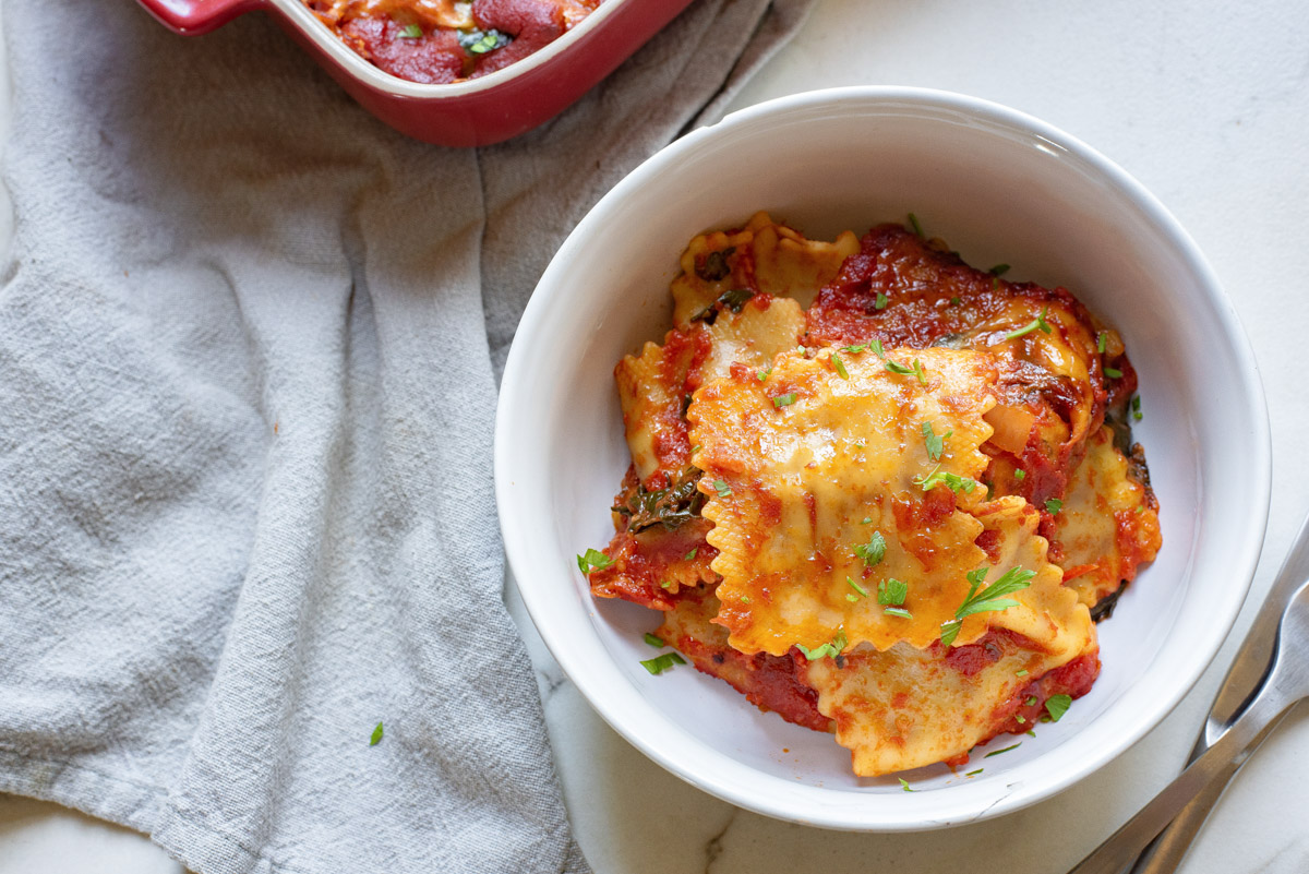 top down view of one serving of baked ravioli in a white bowl