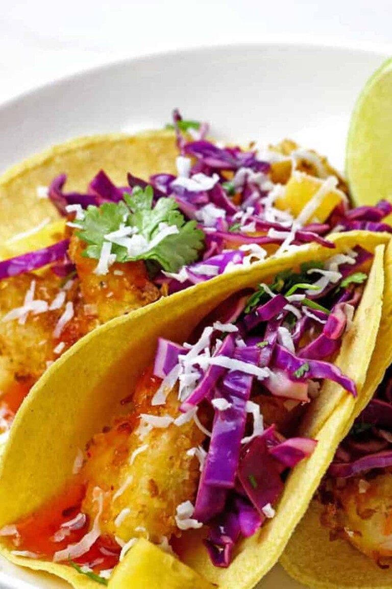 close up view of the completed air fryer coconut shrimp tacos served on a white plate