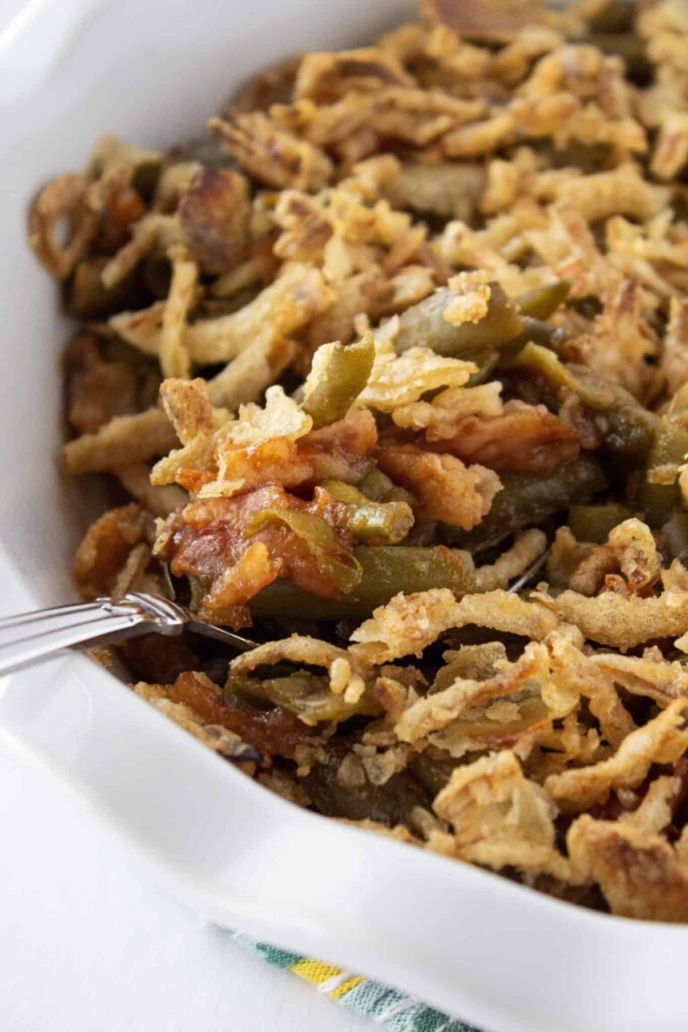 BBQ Green Bean Casserole in a white serving bowl with a serving spoon.
