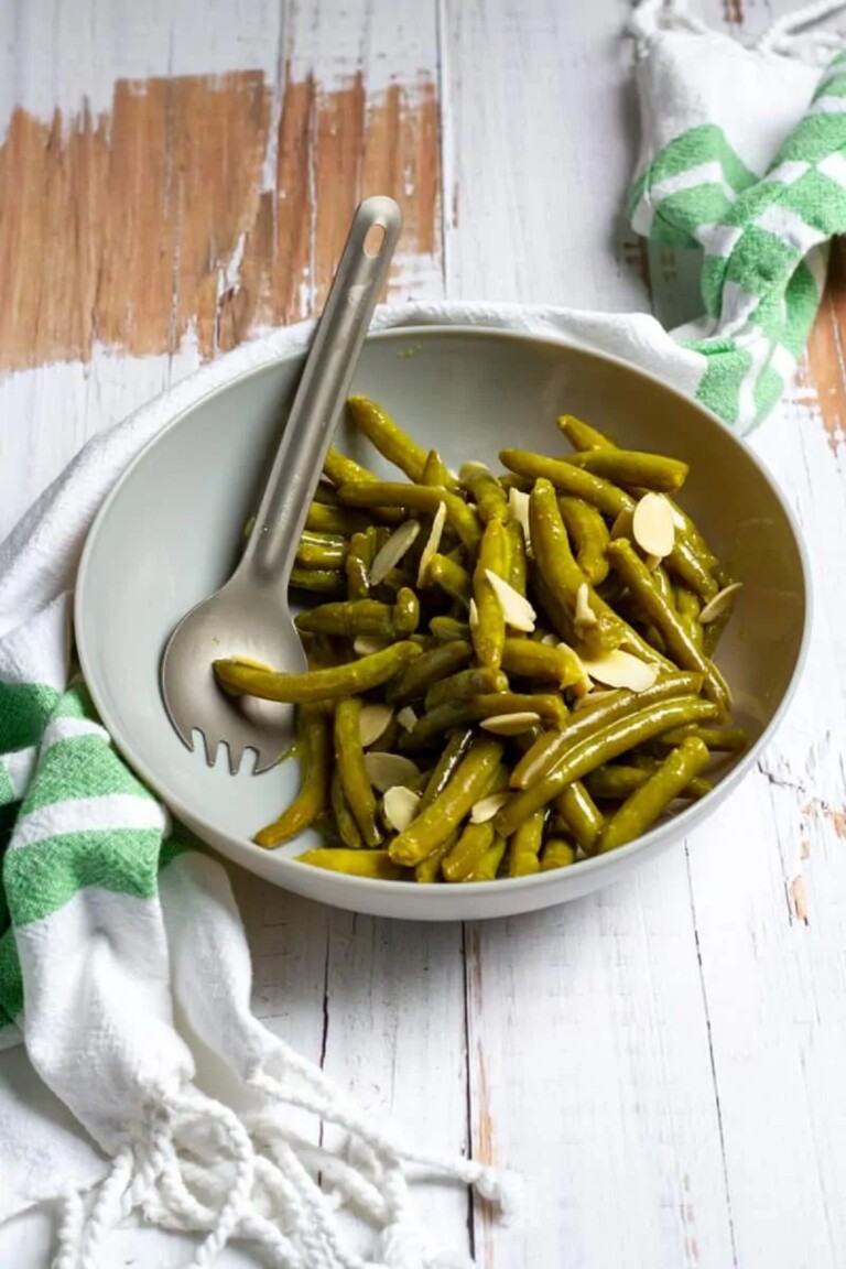 Canned Green Bean Salad in a white bowl with a serving tool.