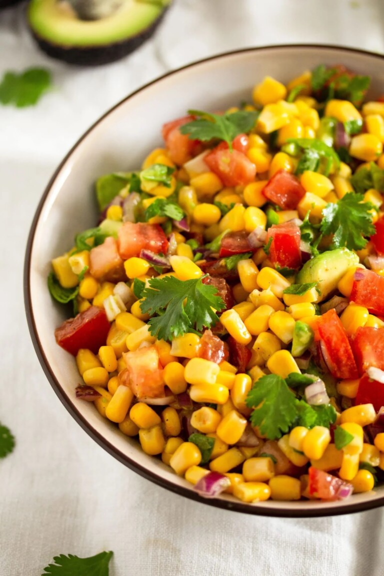 Fiesta corn salad in a white and brown bowl with garnish.