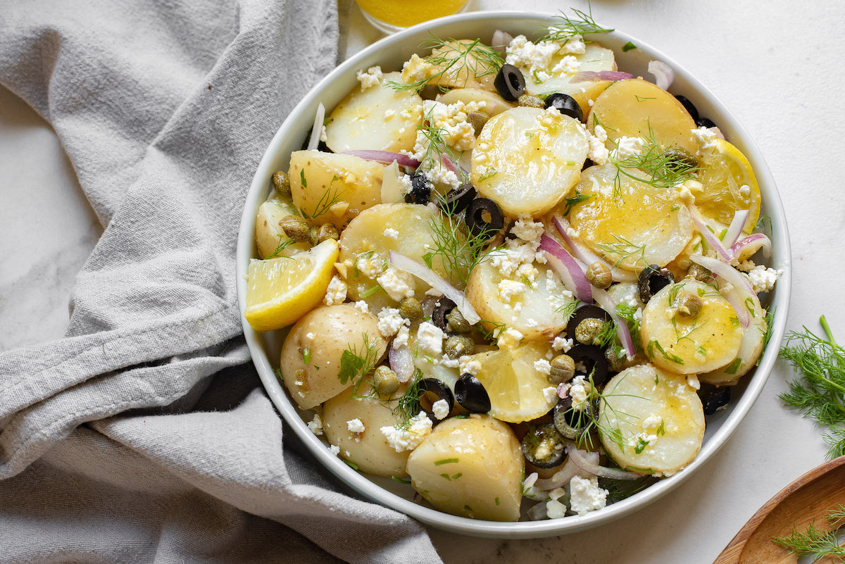 the finished greek potato salad in a white serving bowl