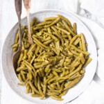 top down view of the completed how to cook canned green beans recipe in a white dish with serving spoons