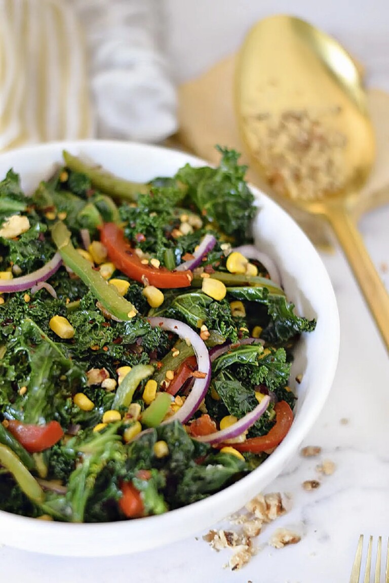 Kale Celebration Vegetable Salad with Walnuts in a white bowl with a gold salad server.