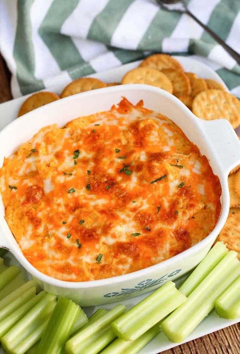 the buffalo chicken dip in a white baking dish served with celery and crackers
