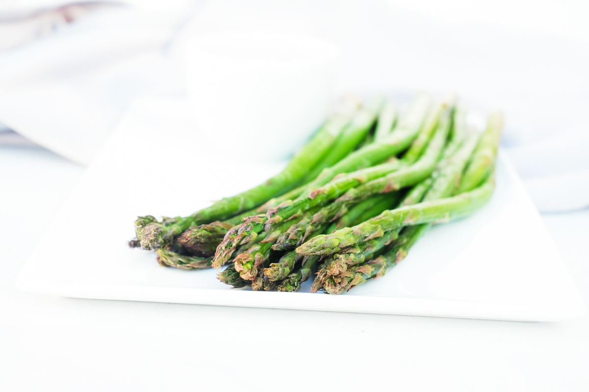side view of the air fryer frozen asparagus on a white dish