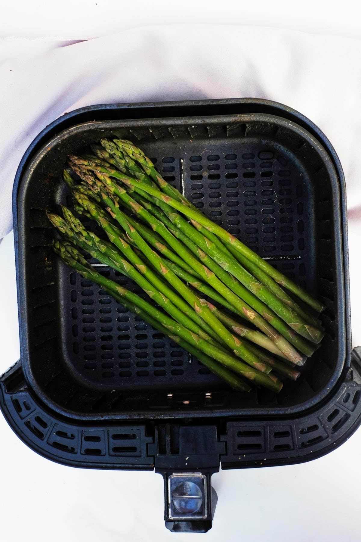 the finished frozen asparagus in air fryer basket and ready to serve