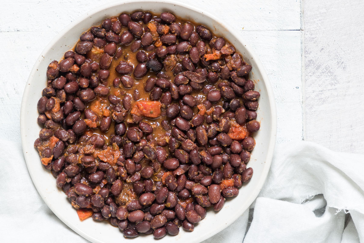 the finished version of how to cook canned black beans served in a white bowl