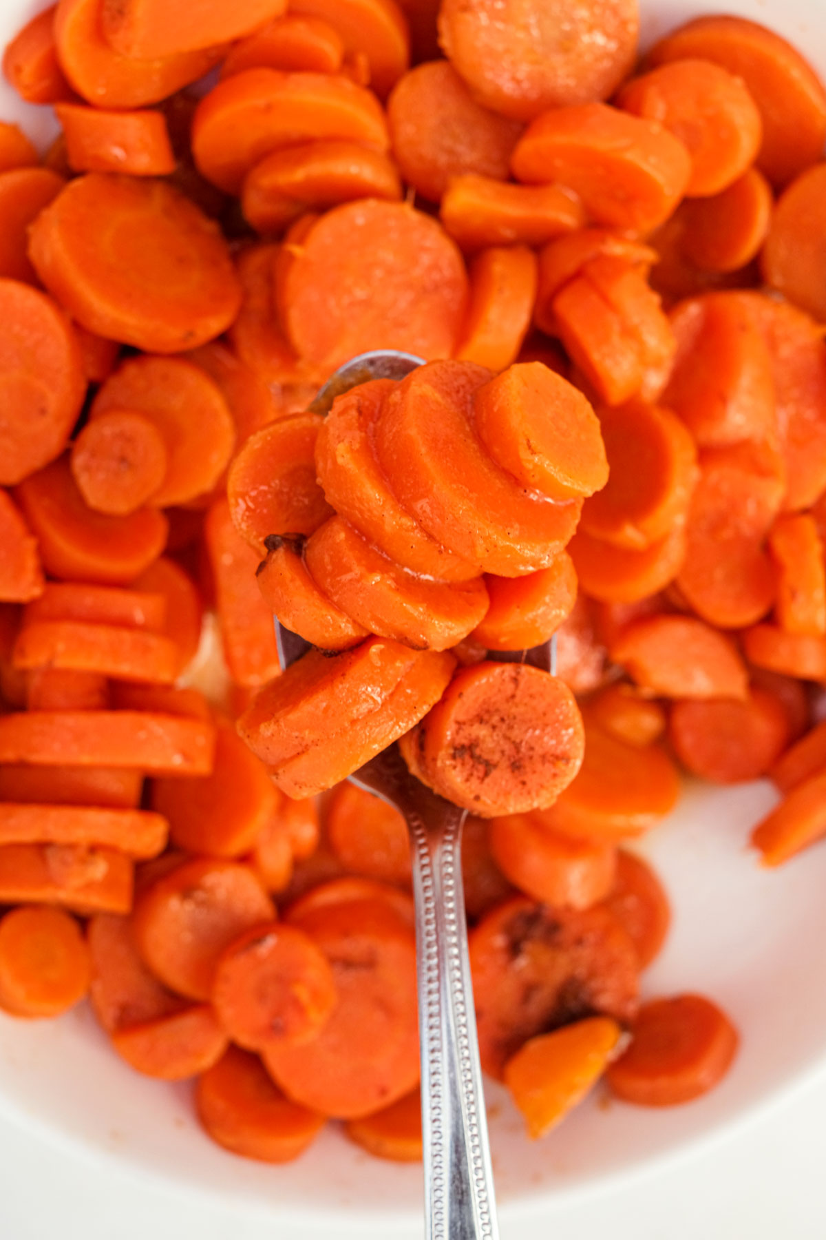 close up of a spoon removing some of the how to cook canned carrots