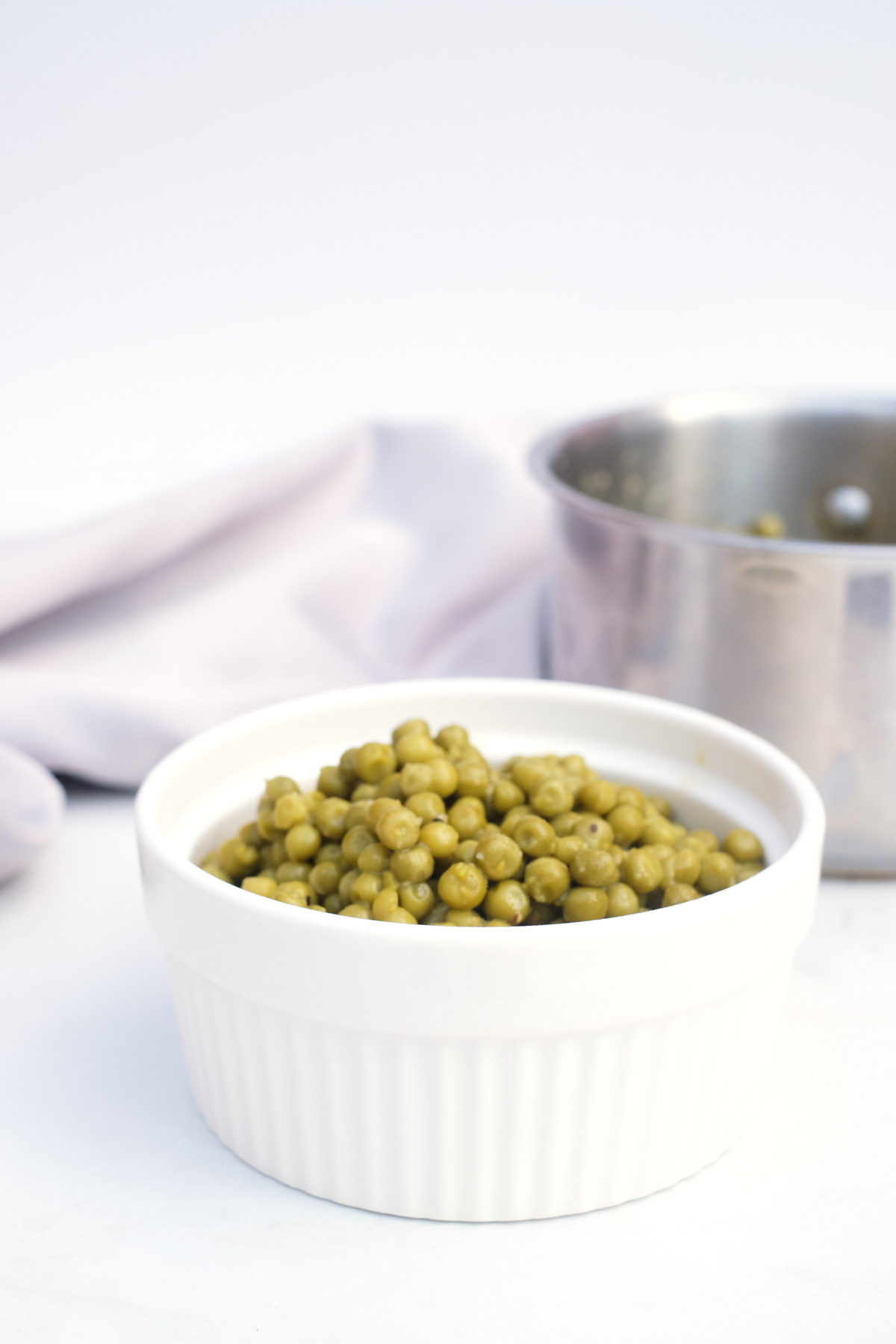 the completed how to cook canned peas recipe in a white serving dish
