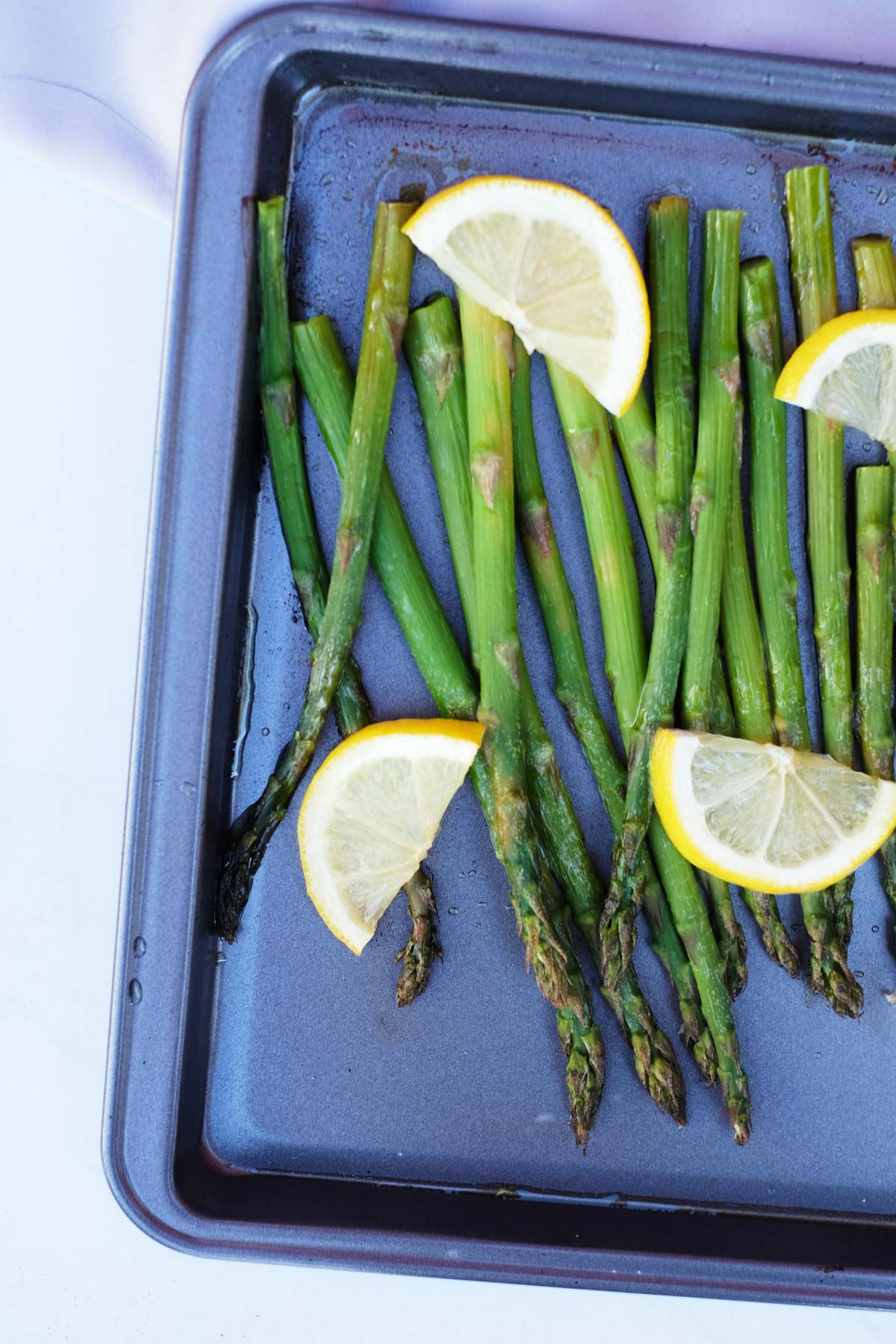 top down view of asparagus and lemon wedges on a baking tray