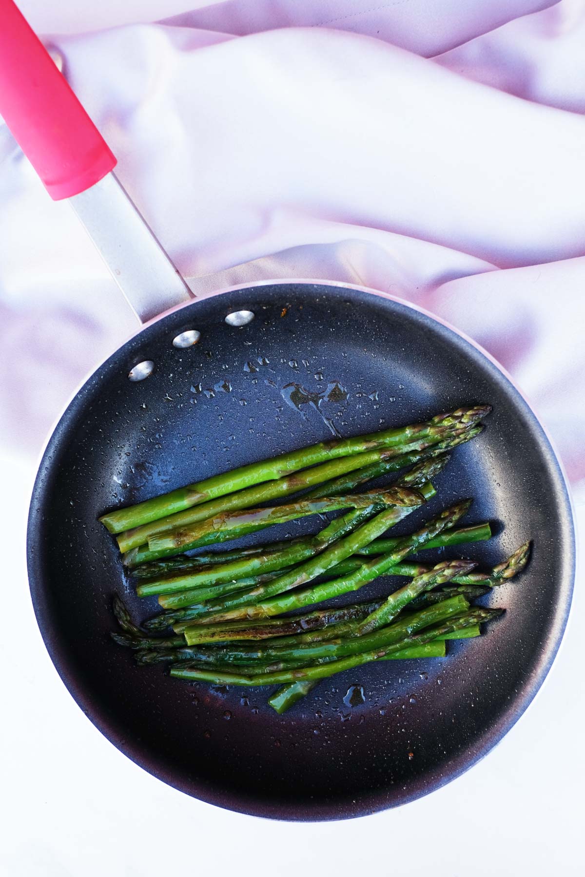 top down view of a skillet filled with cooked frozen asparagus