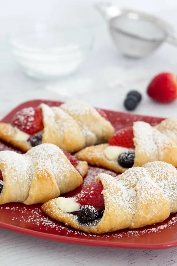 four of the cream cheese crescent rolls with berries on a red plate