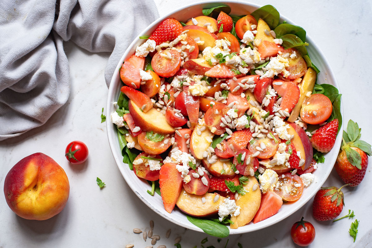 the finished tomato feta salad with peach slices and strawberries