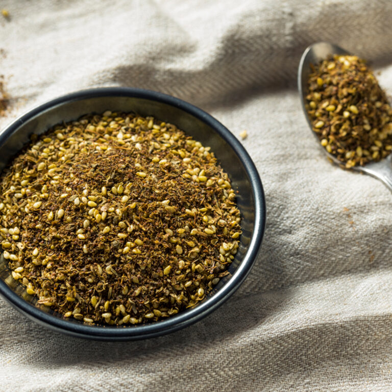 A bowl of Za’atar seasoning with a spoon beside it.