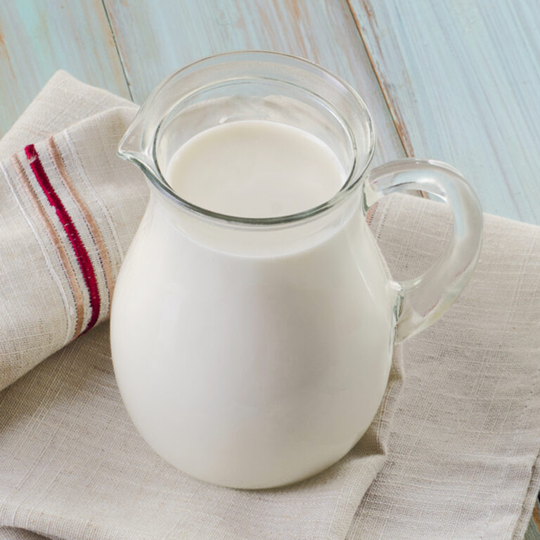 A glass pitcher of buttermilk sitting on a kitchen towel