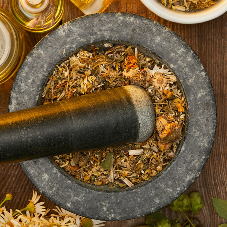 Overhead view of a stone pestle full of dried herbs with a mortar in it.