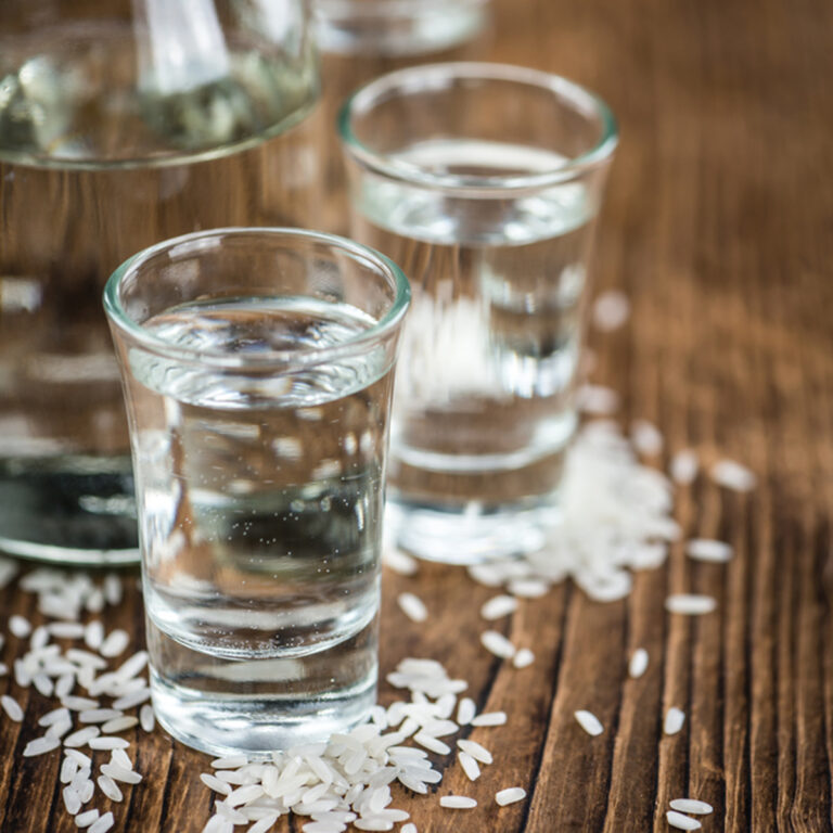 Two small glasses of sake with grains of rice scattered around them