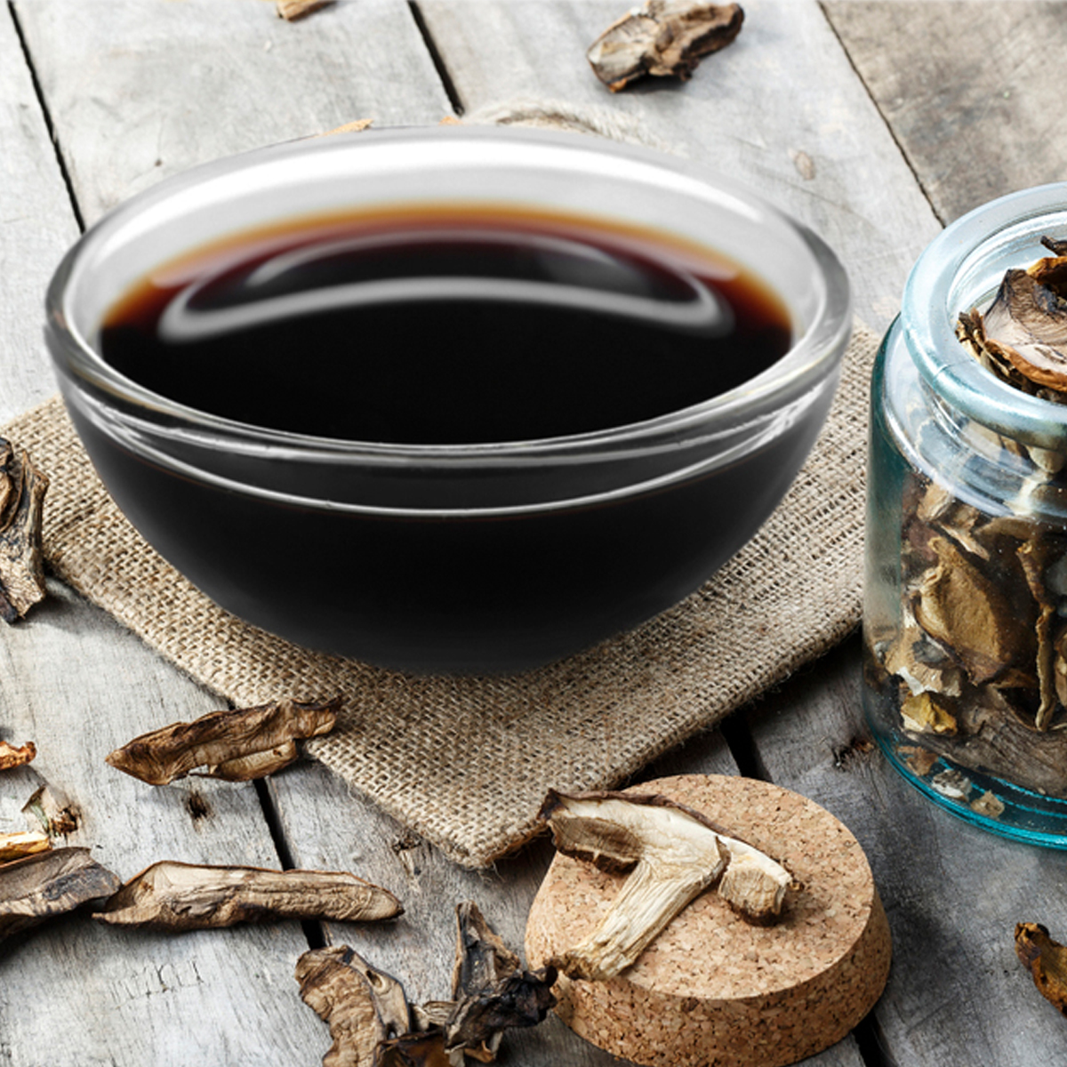 a glass bowl of mushroom sauce on a burlap placemat