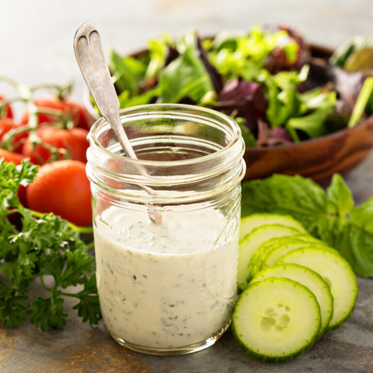 A jar of ranch dressing surrounded by various vegetables
