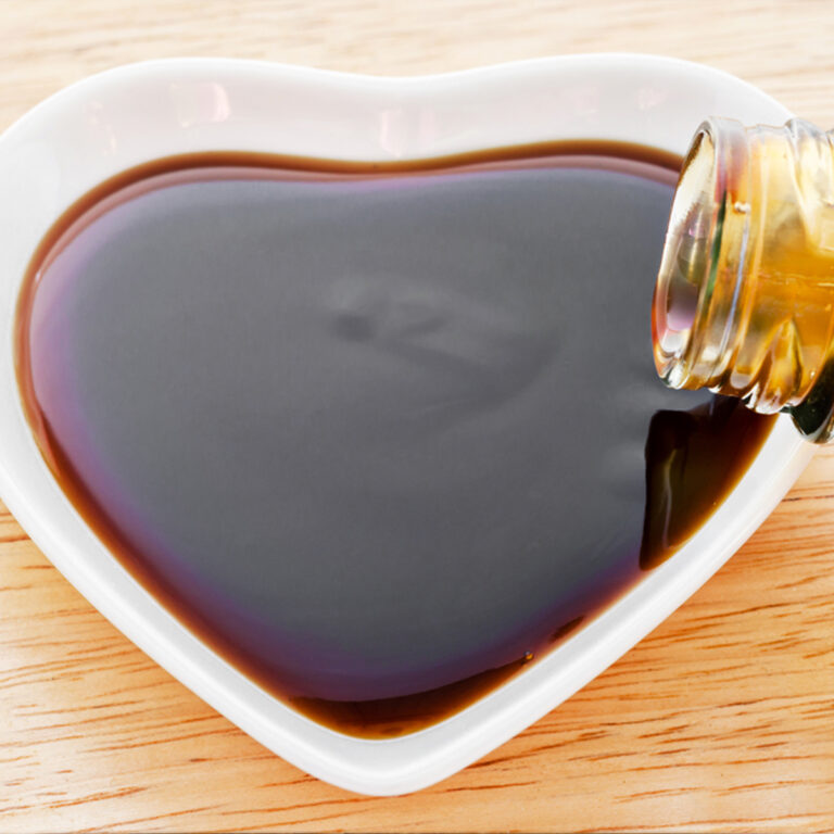 Vegetarian oyster sauce being poured from a bottle into a heart-shaped dish