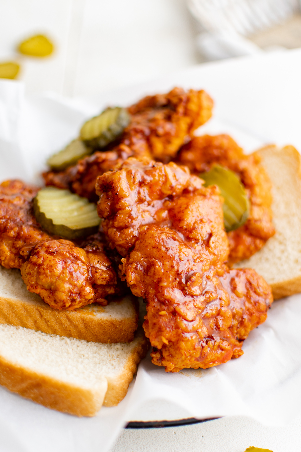 close up view of air fryer nashville hot chicken served on white bread and topped with pickles