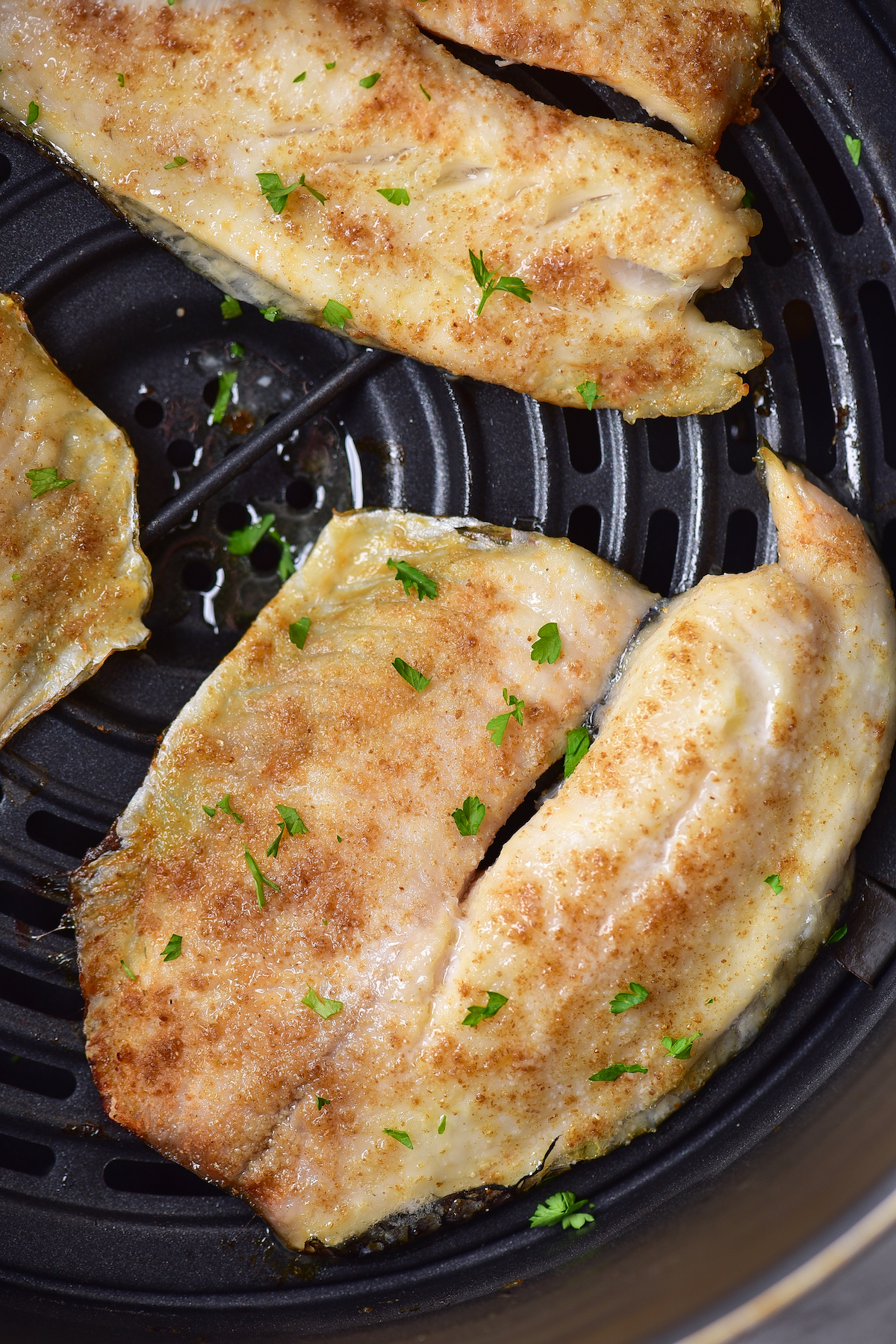 close up view of the cooked tilapia in air fryer basket